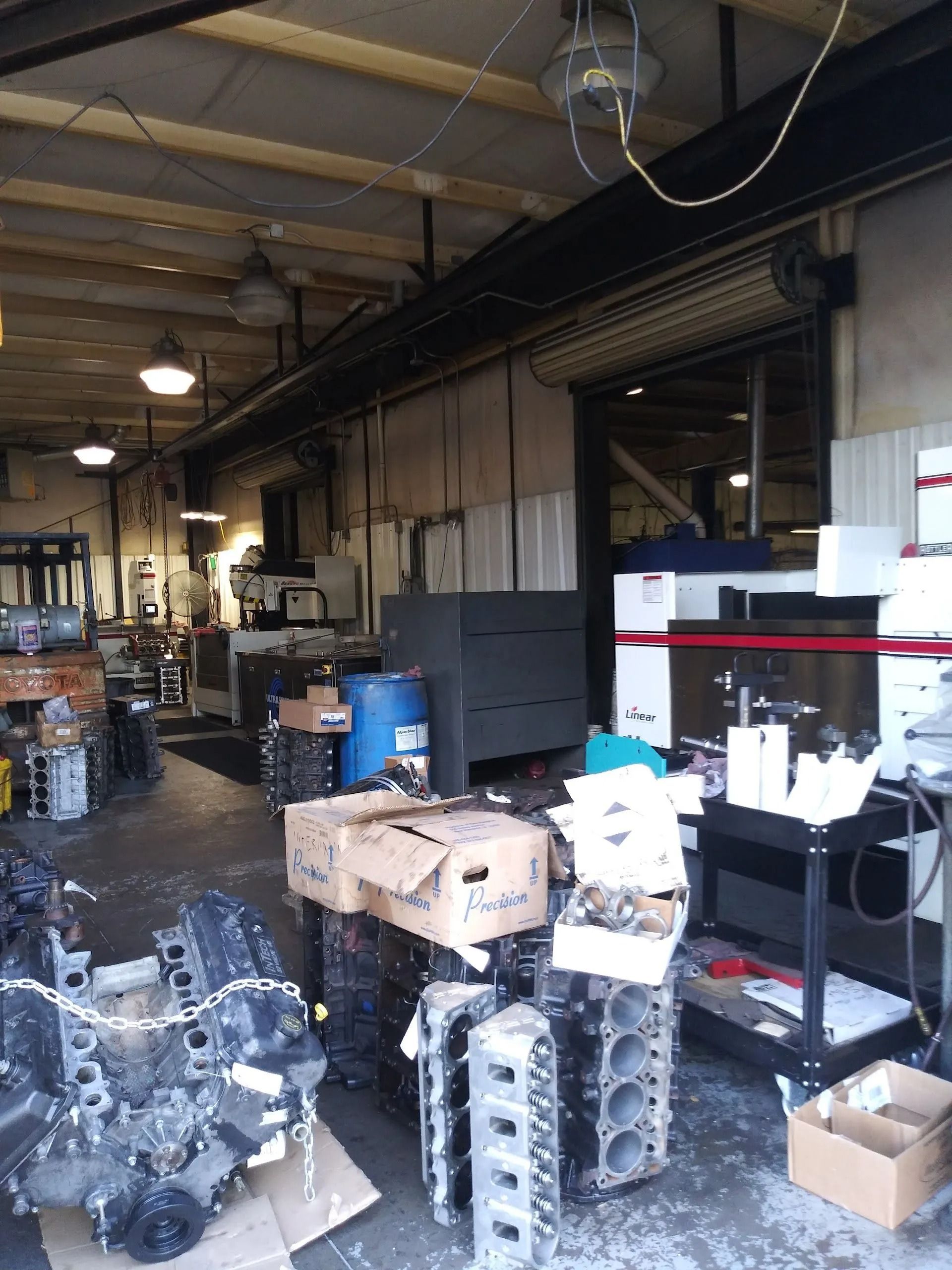 Industrial workshop with engine parts, cardboard boxes, and shelving in a cluttered warehouse aisle