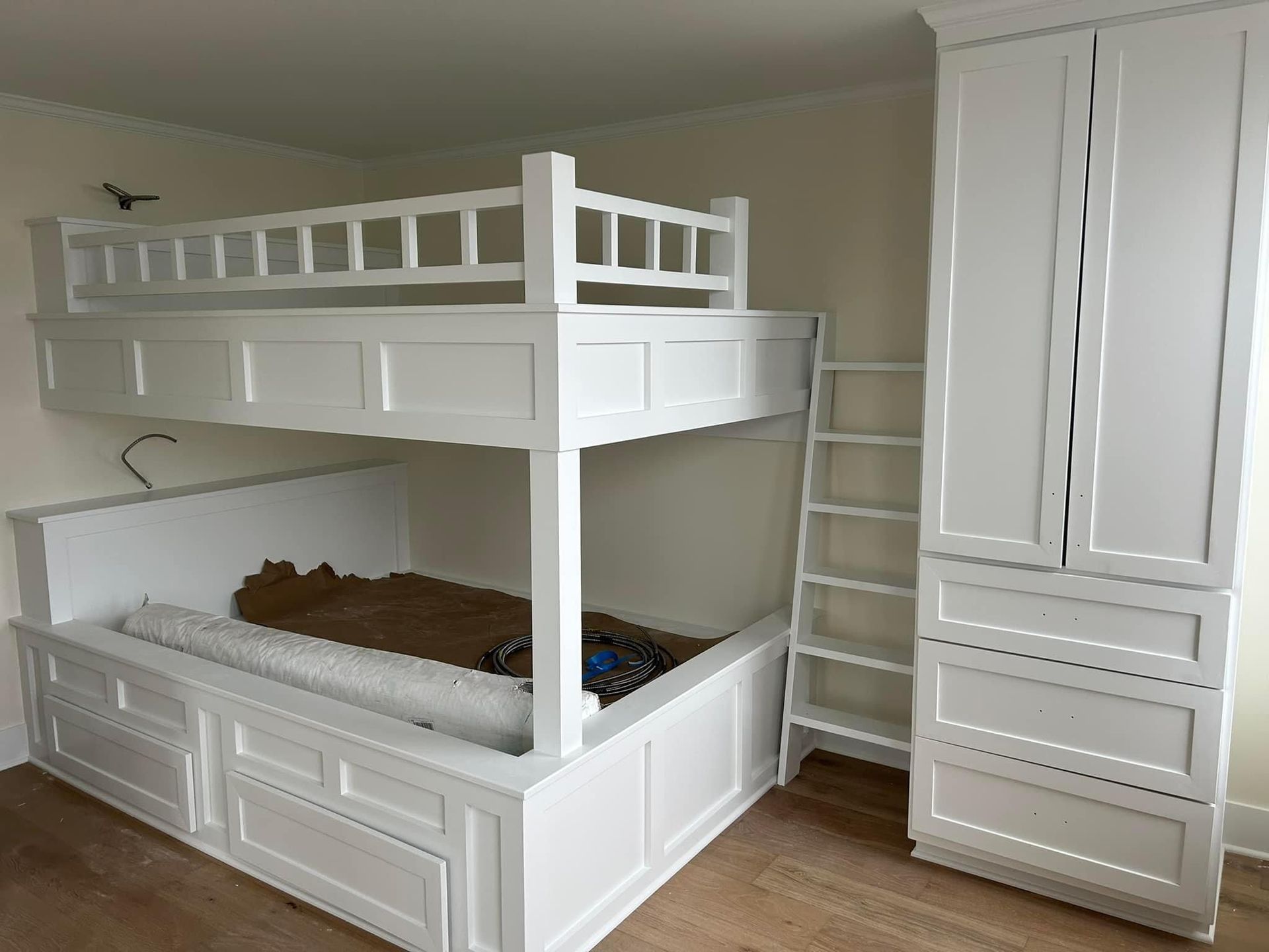 A white bunk bed with a ladder in a bedroom