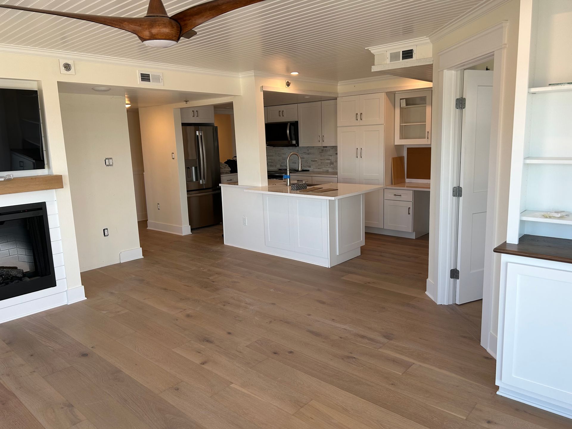 A living room with hardwood floors, a fireplace and a ceiling fan