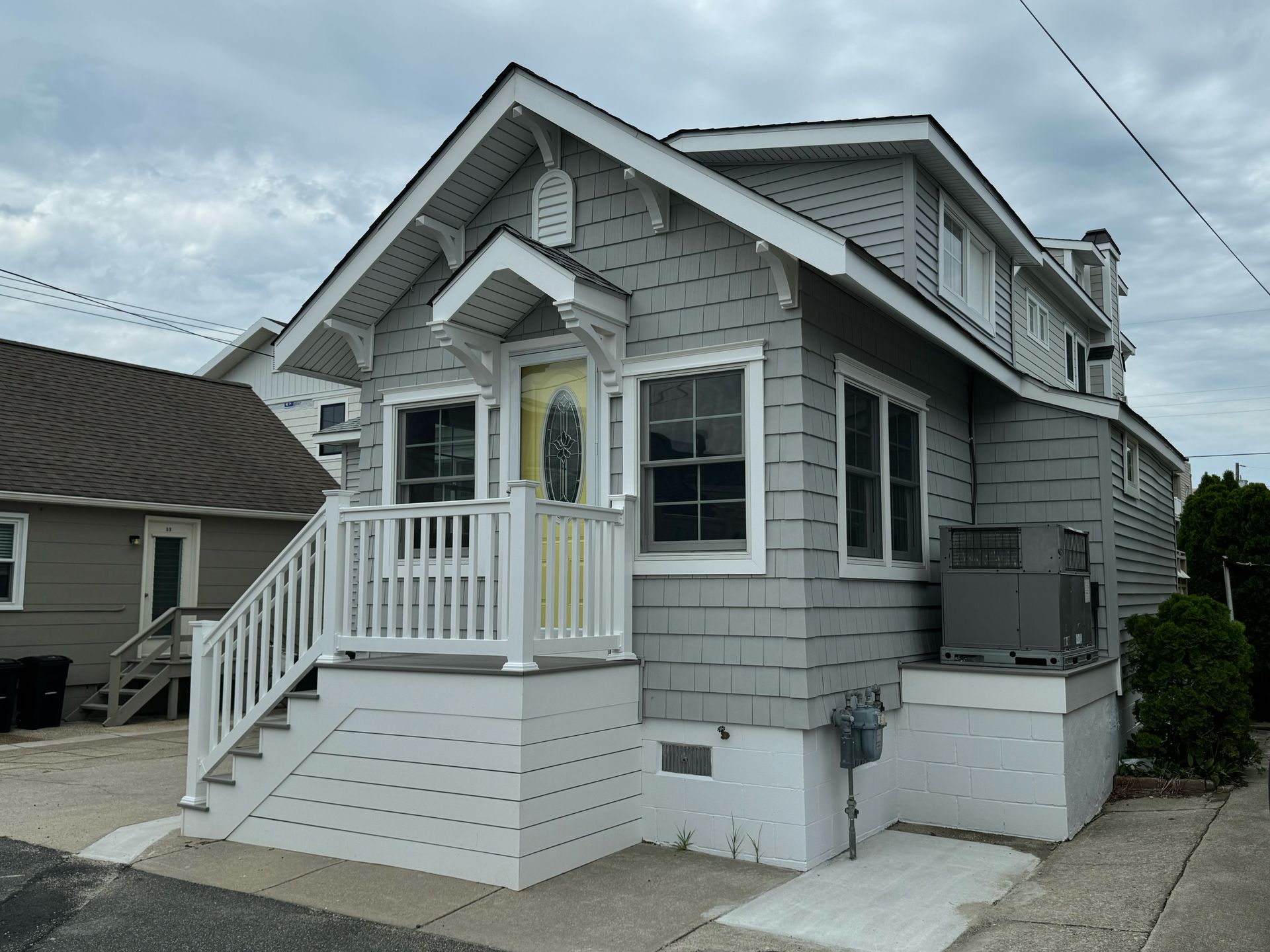 A small house with a yellow door and a white porch