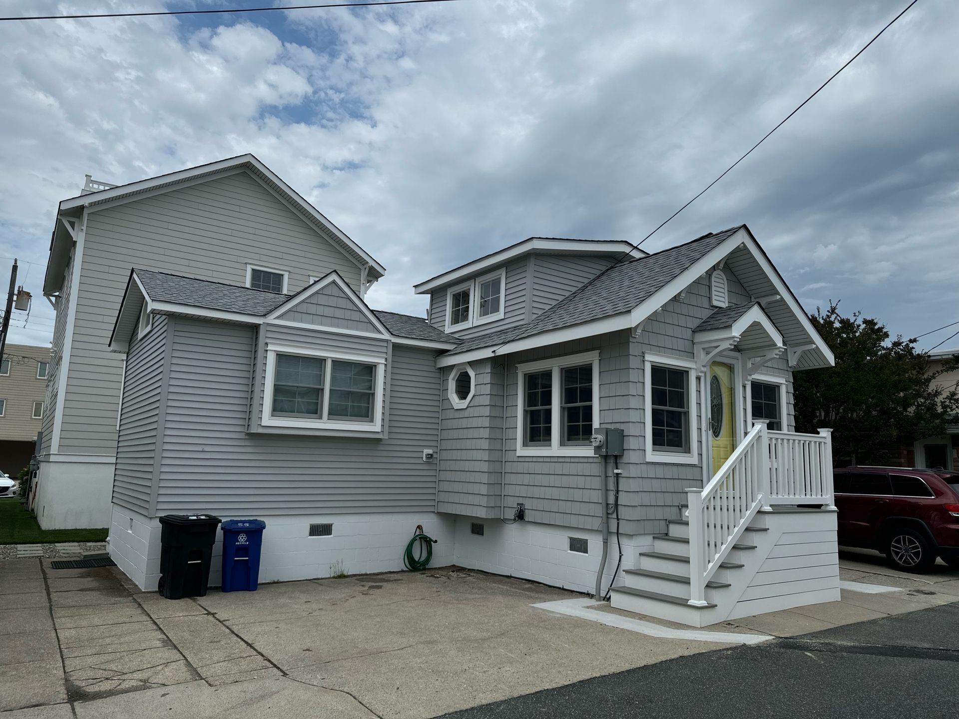 A gray and white house with a yellow door and stairs
