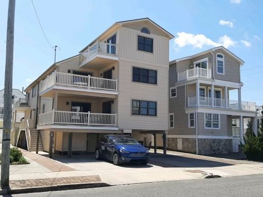 A blue car is parked in front of a large house
