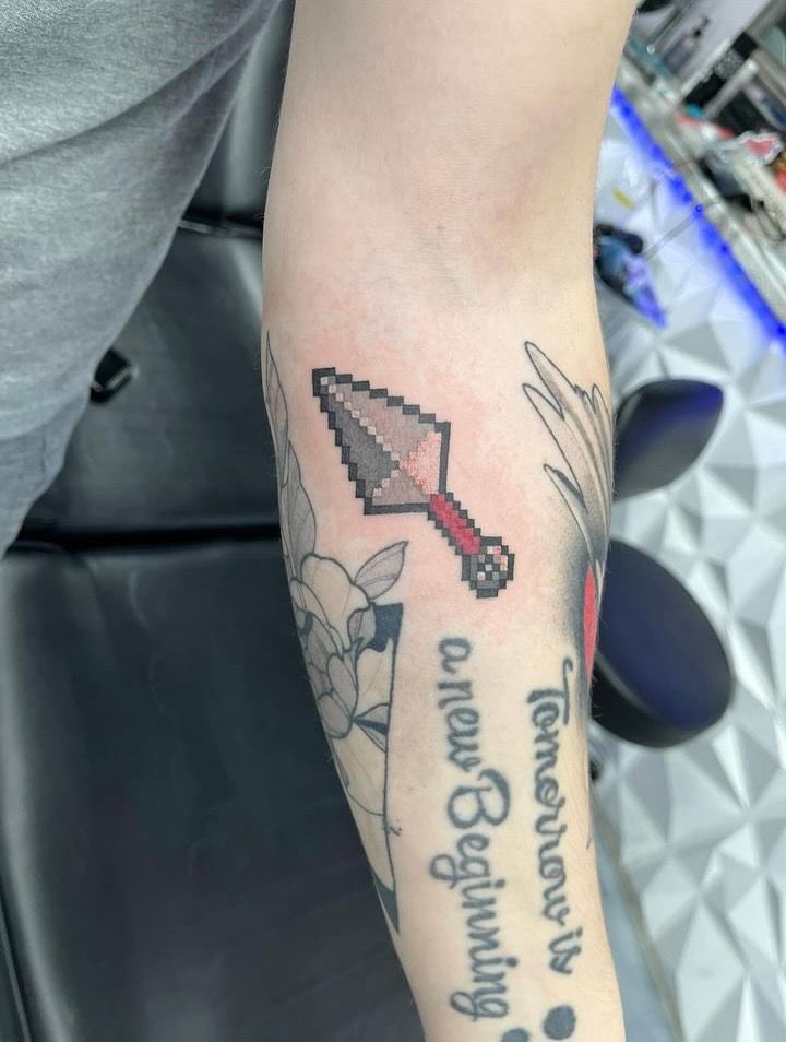 Pixelated pitchfork tattoo on an arm