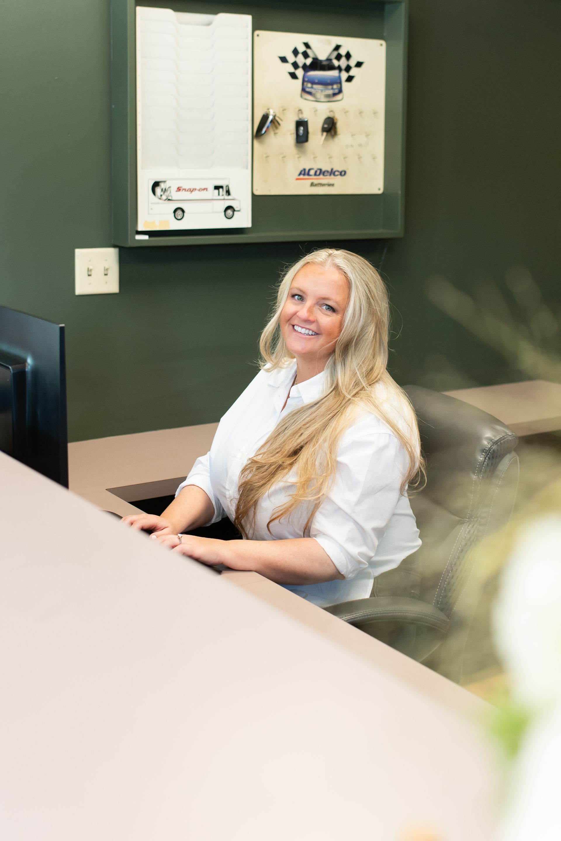 Smiling receptionist at a desk in a green-walled office area
