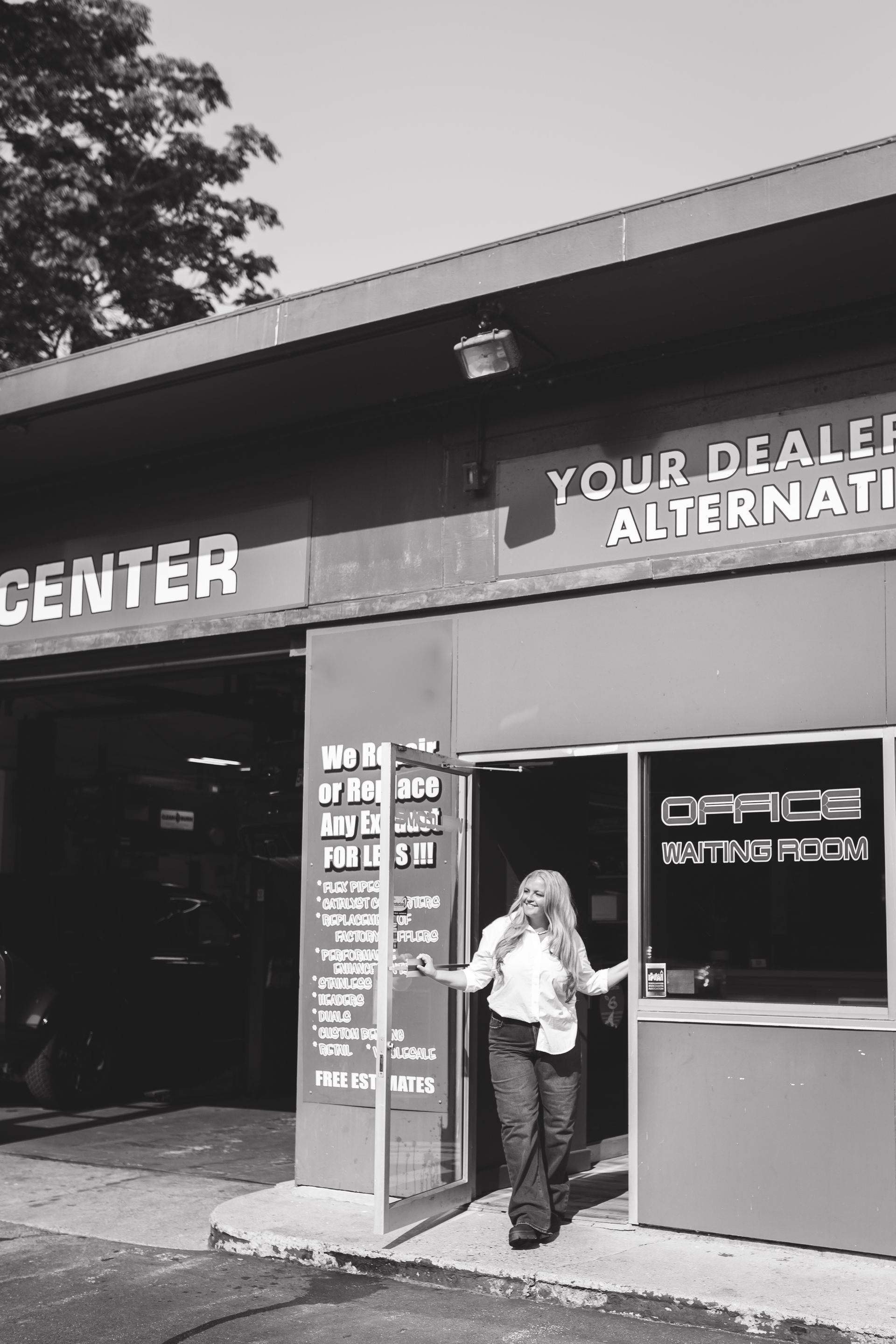 Person entering a storefront at a dealership, standing by a door under a sign reading “Your dealer alternative.”