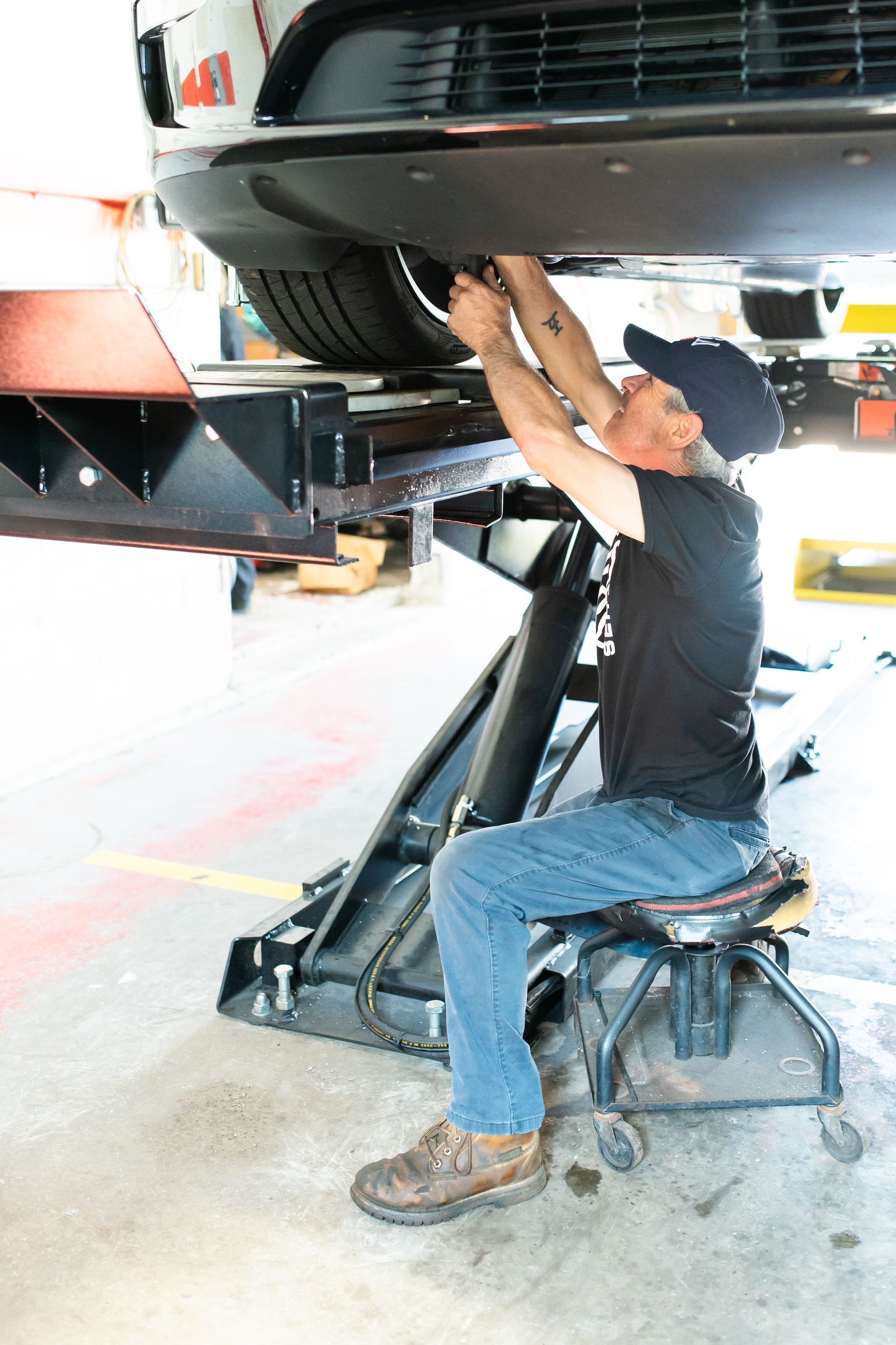Mechanic under a raised car, checking the underside with a lift in an auto shop