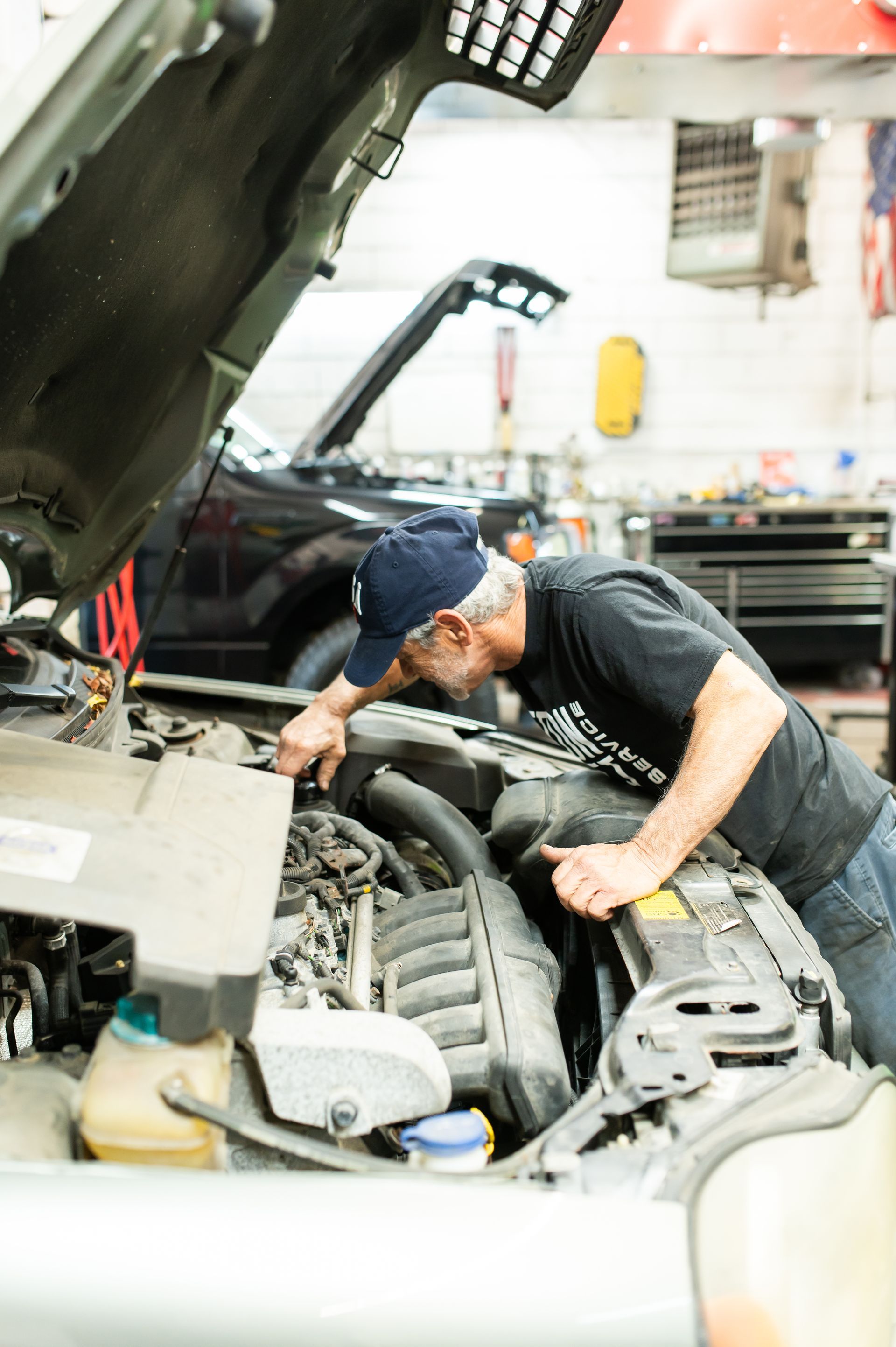 Mechanic inspecting a car engine with the hood open in a garage