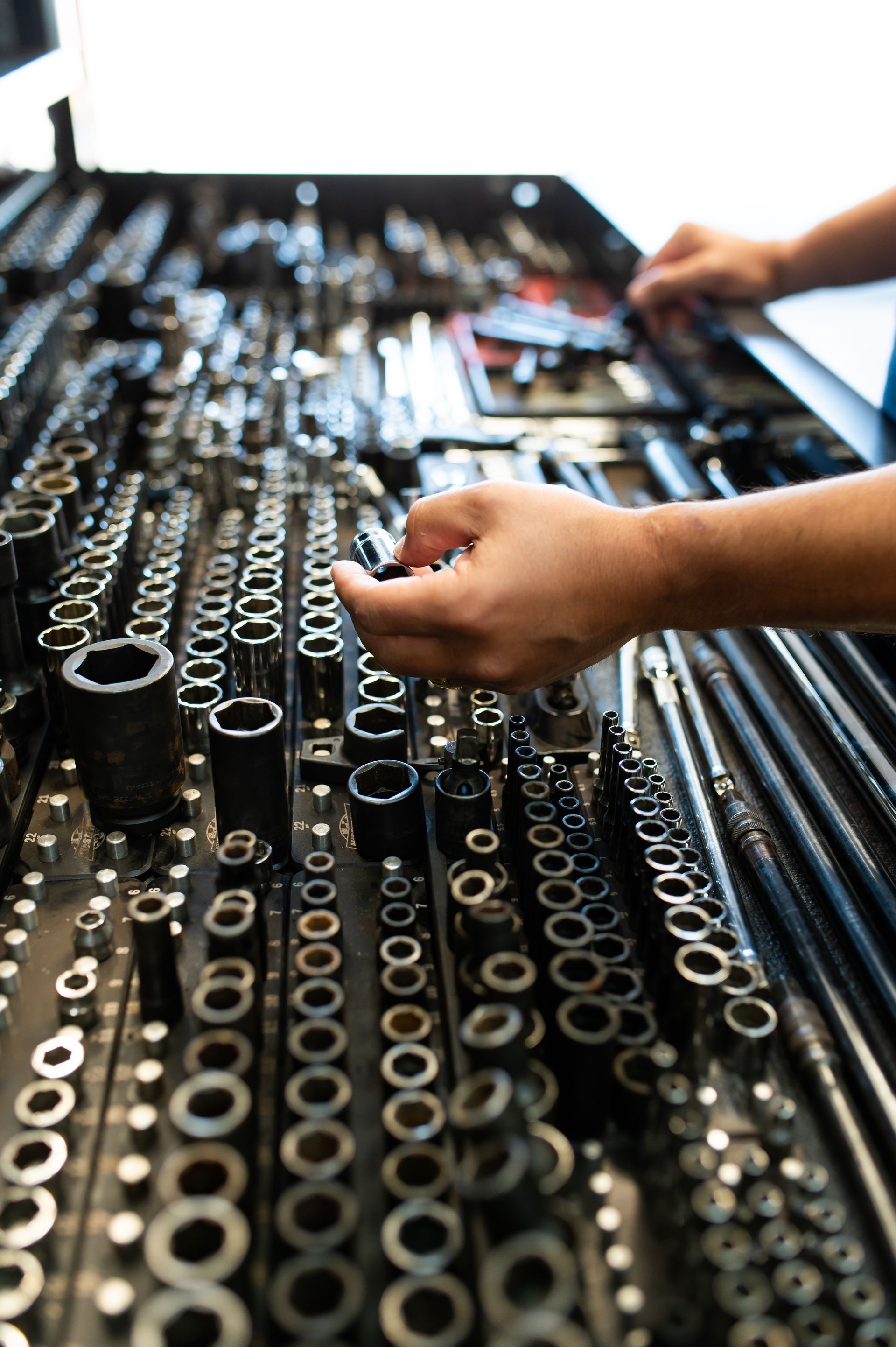 Hands arranging socket wrenches in a tool tray on a workbench