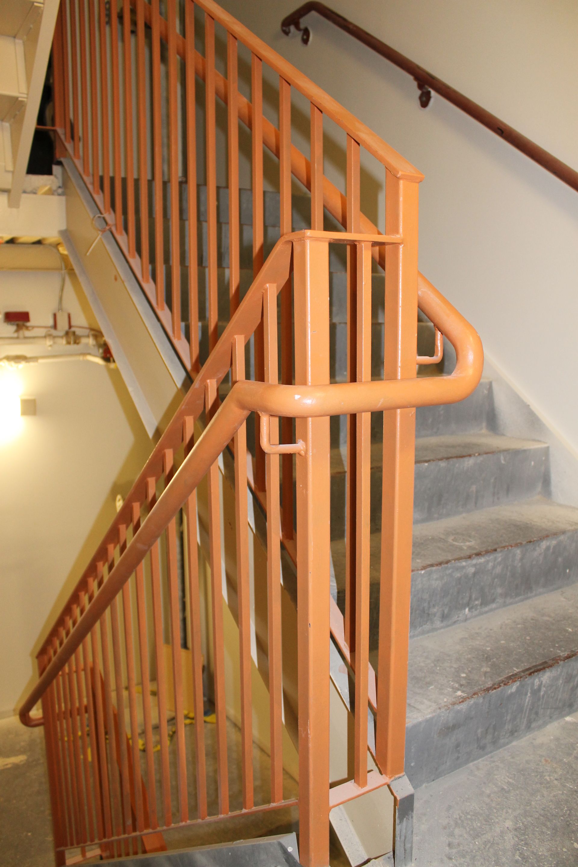 Wooden stair railing beside carpeted stairs in an indoor building corridor