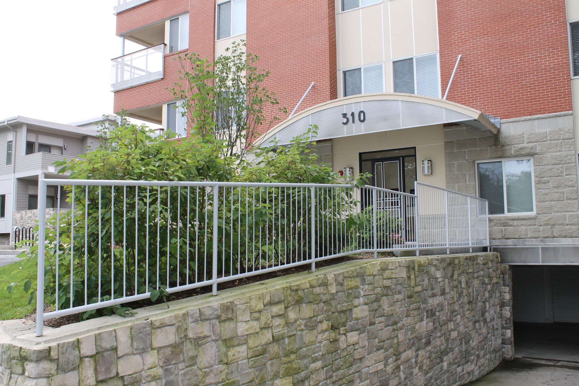 Apartment entrance with wheelchair ramp, metal railing, and stone retaining wall under building number 510