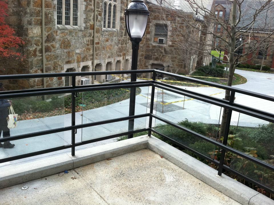 Stone courtyard with black railing, lamp post, and a stone building in the background