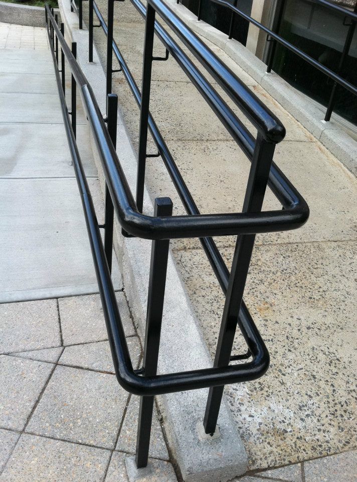 Black metal handrails along an outdoor concrete ramp and walkway