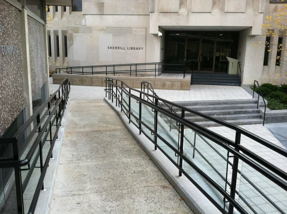 Accessible ramp leading to a building entrance with handrails and steps nearby