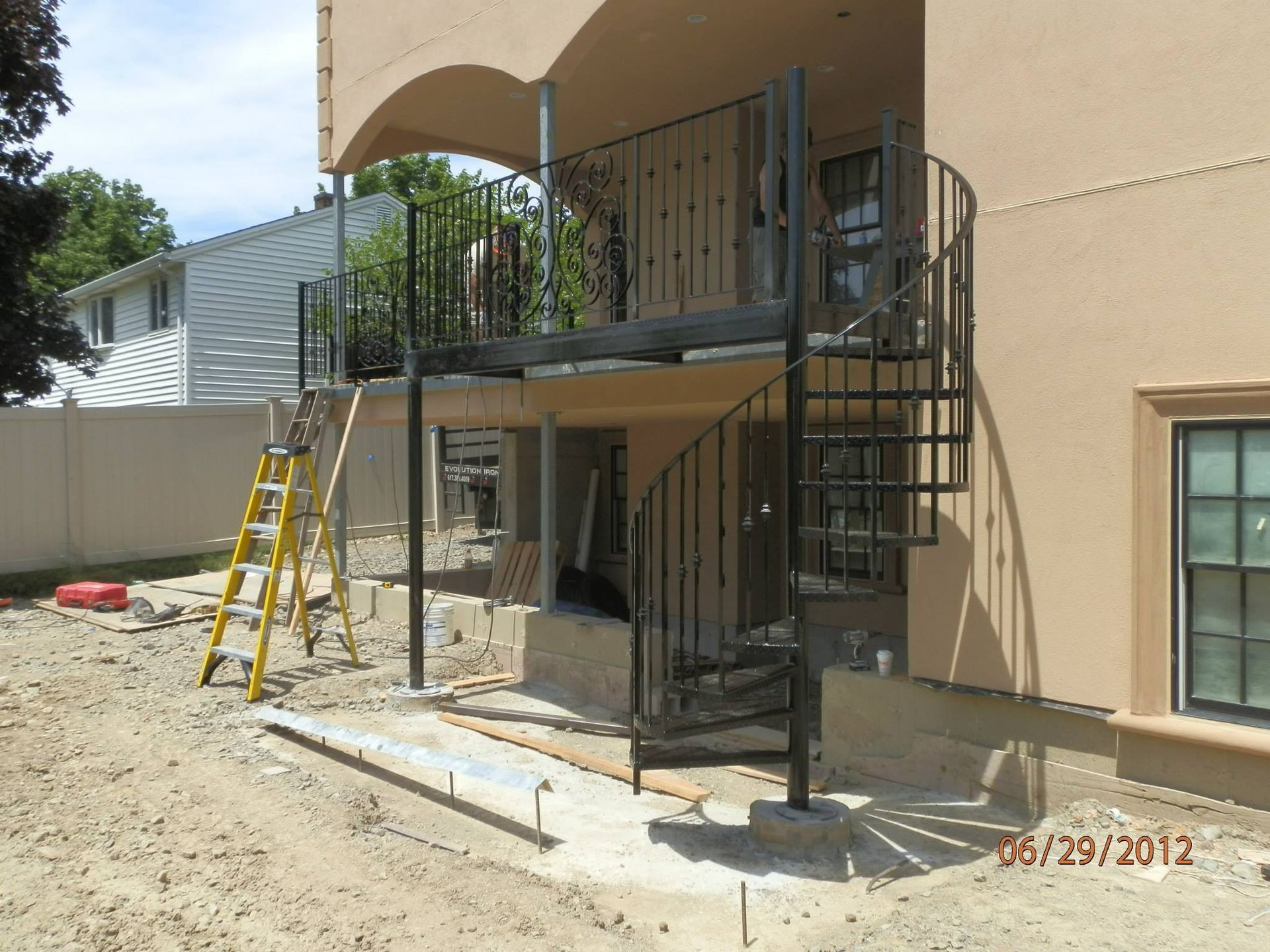Metal accessibility ramp and stairs under construction beside a beige building, with ladders nearby