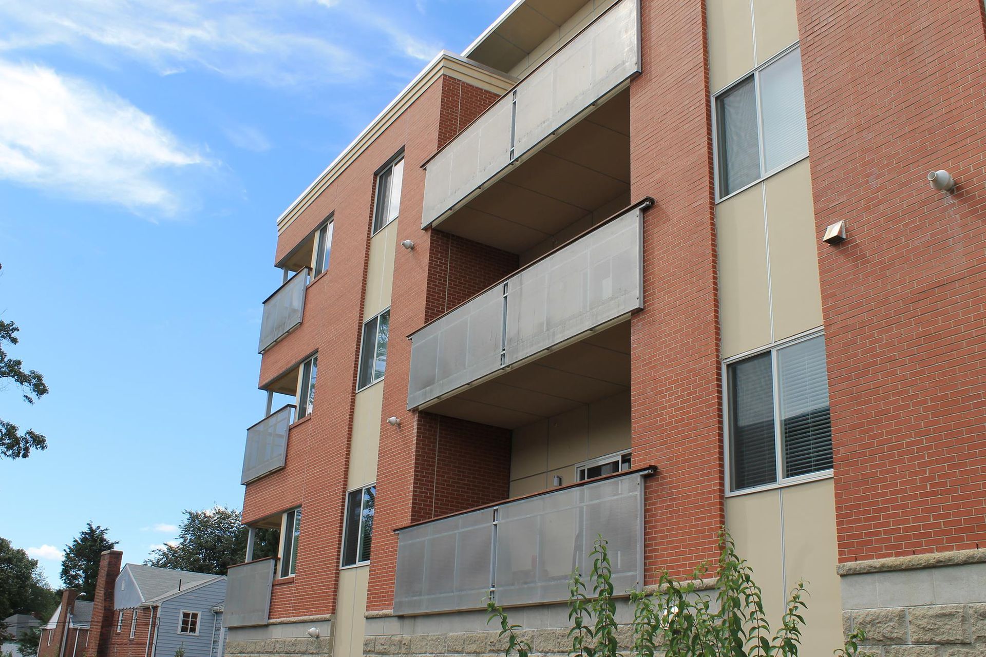 Brick apartment building with balconies and windows under a blue sky