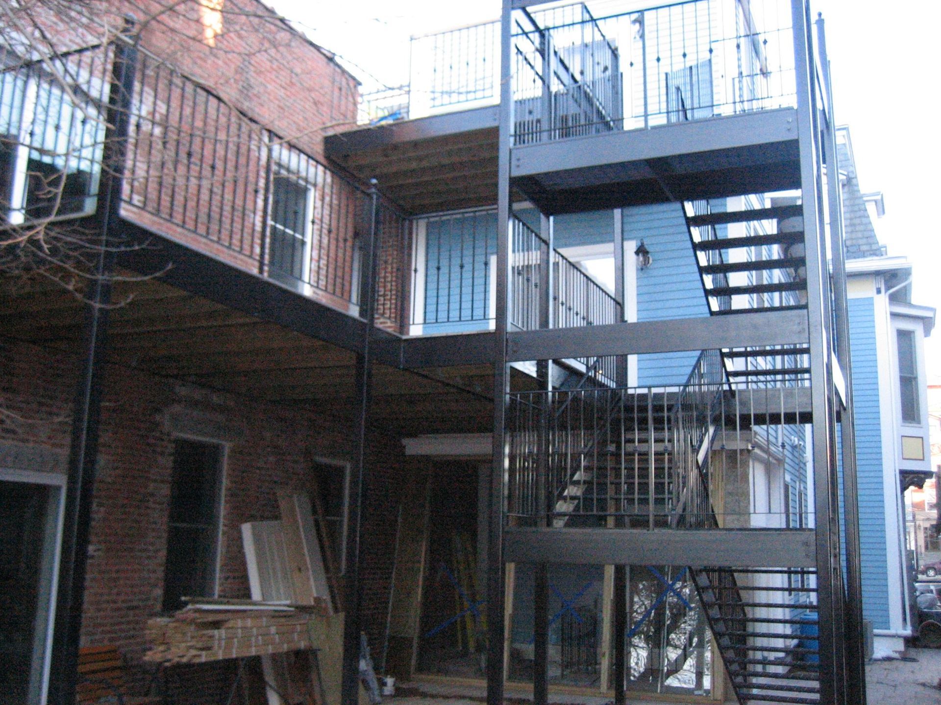 Narrow brick alley with a metal fire escape and staircase between old buildings