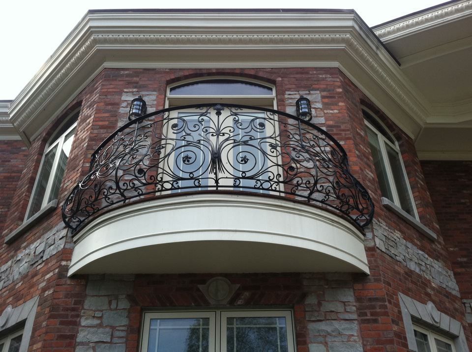 Brick house facade with ornate iron balcony and arched windows