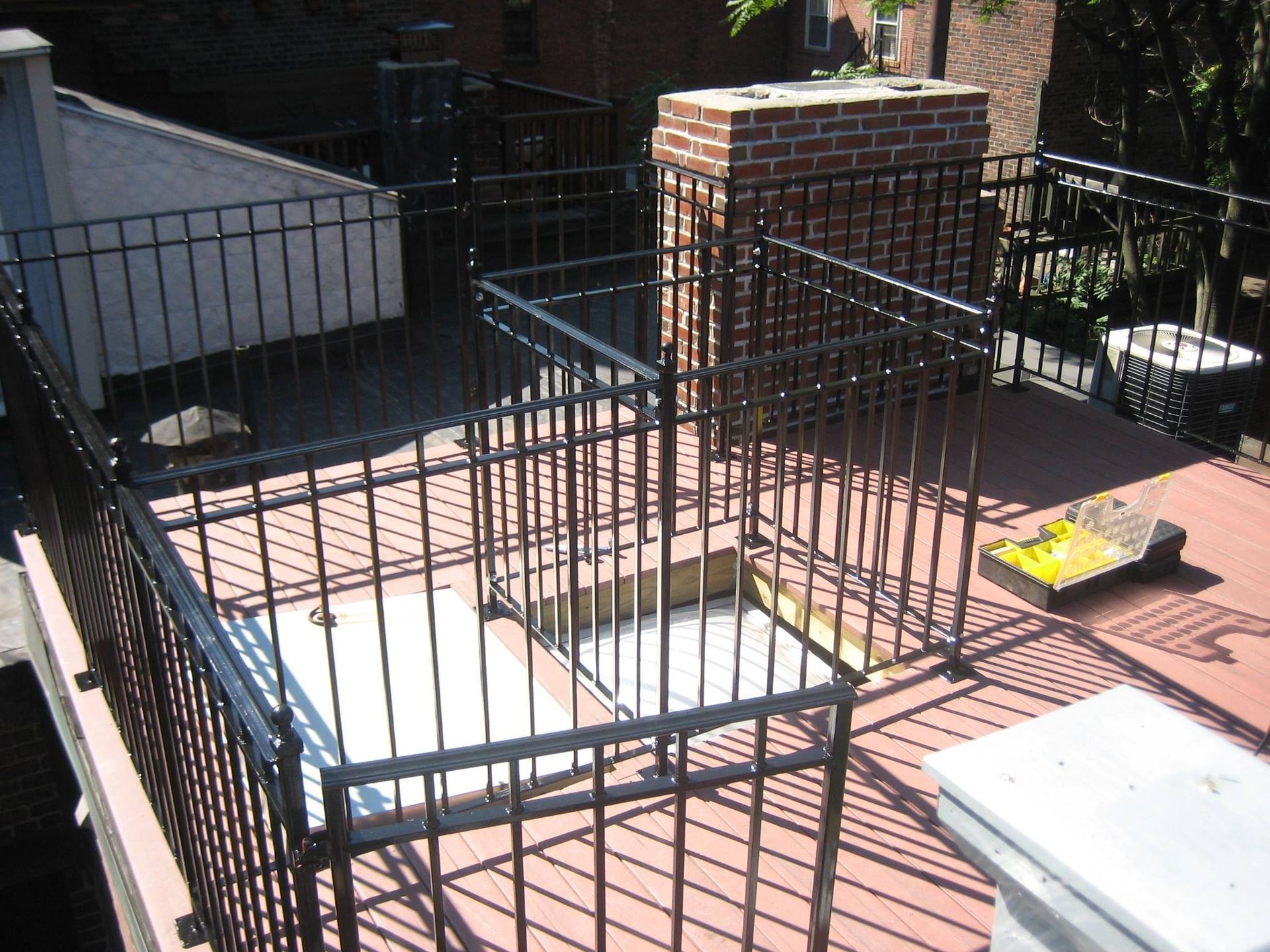 Black metal fenced patio area with brick columns, steps, and a white table on the right