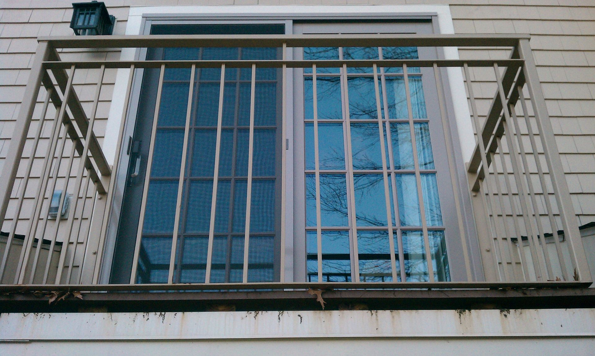 Metal balcony railing in front of a building with blue glass windows