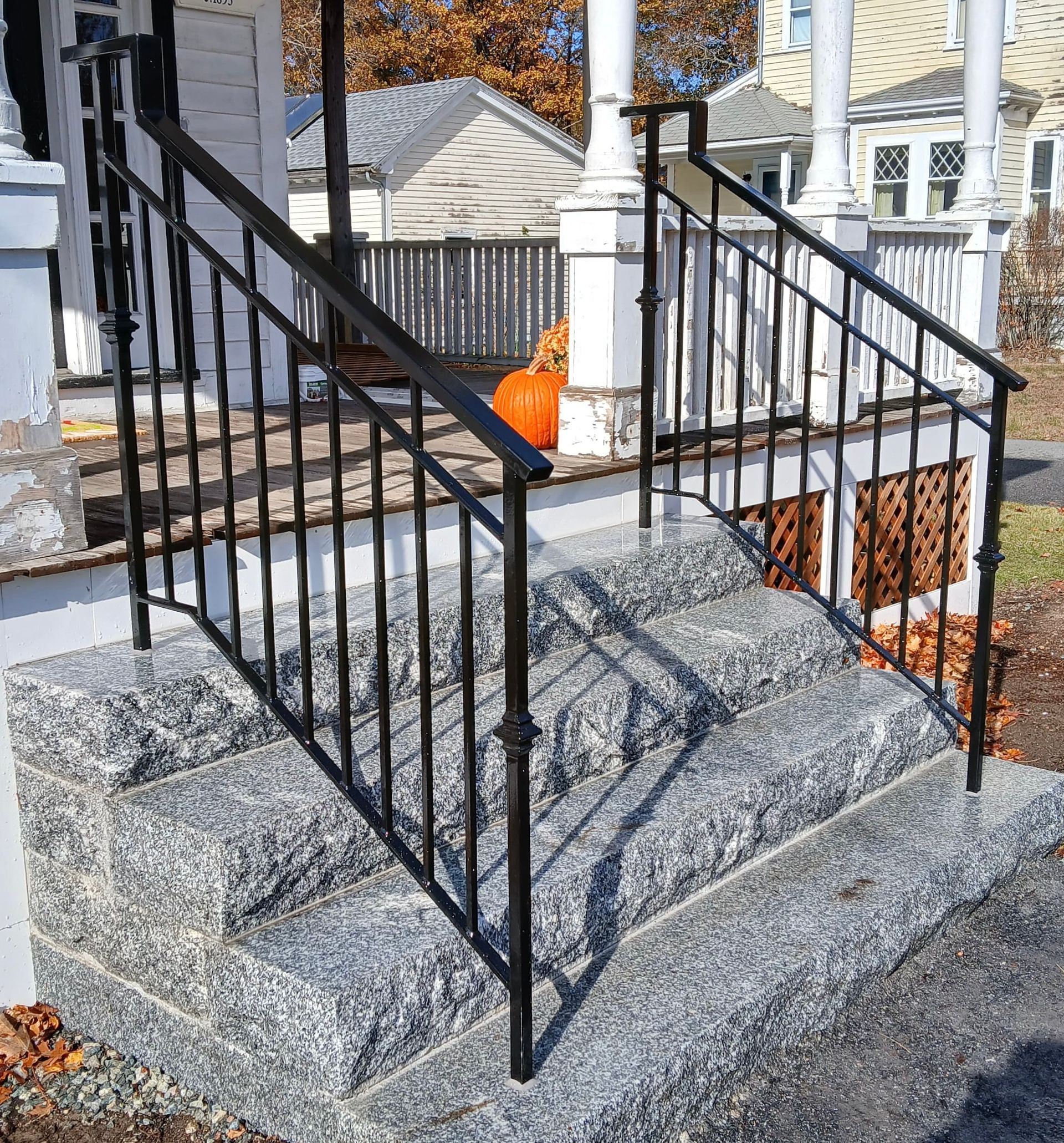 Black wrought-iron railings on a granite porch with steps and a small orange object near the entrance