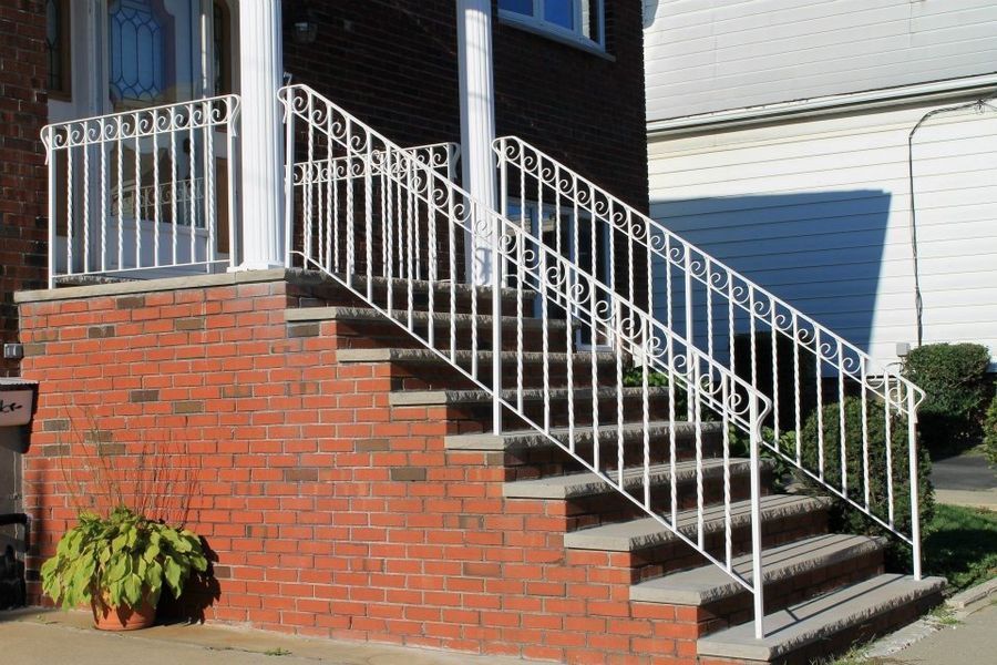 White metal railings line the brick stairs leading to a building's entrance.