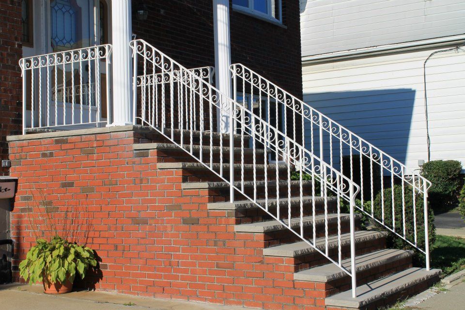 Brick front steps with white railing leading to a house entrance