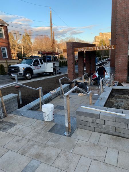 Workers install outdoor railings and stonework at the entrance of 
