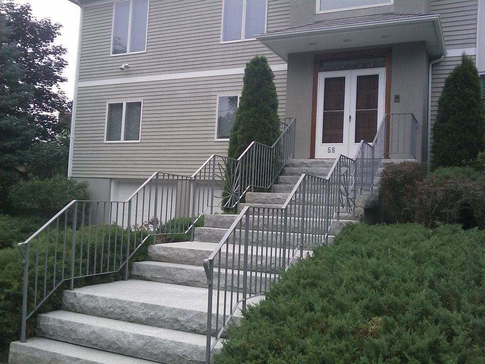 Front steps leading to a beige apartment entrance with metal railings and shrubbery