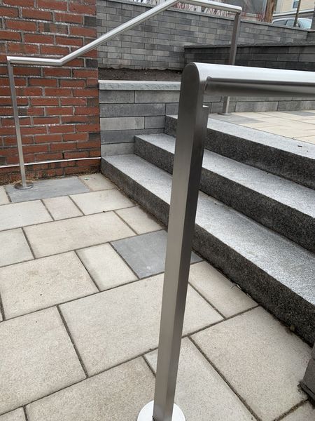 Metal railings along outdoor stone stairs and a brick wall.