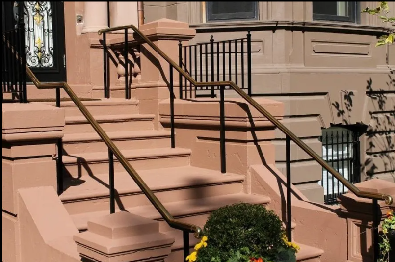 Pink townhouse stoop with black railings and steps leading to the front door