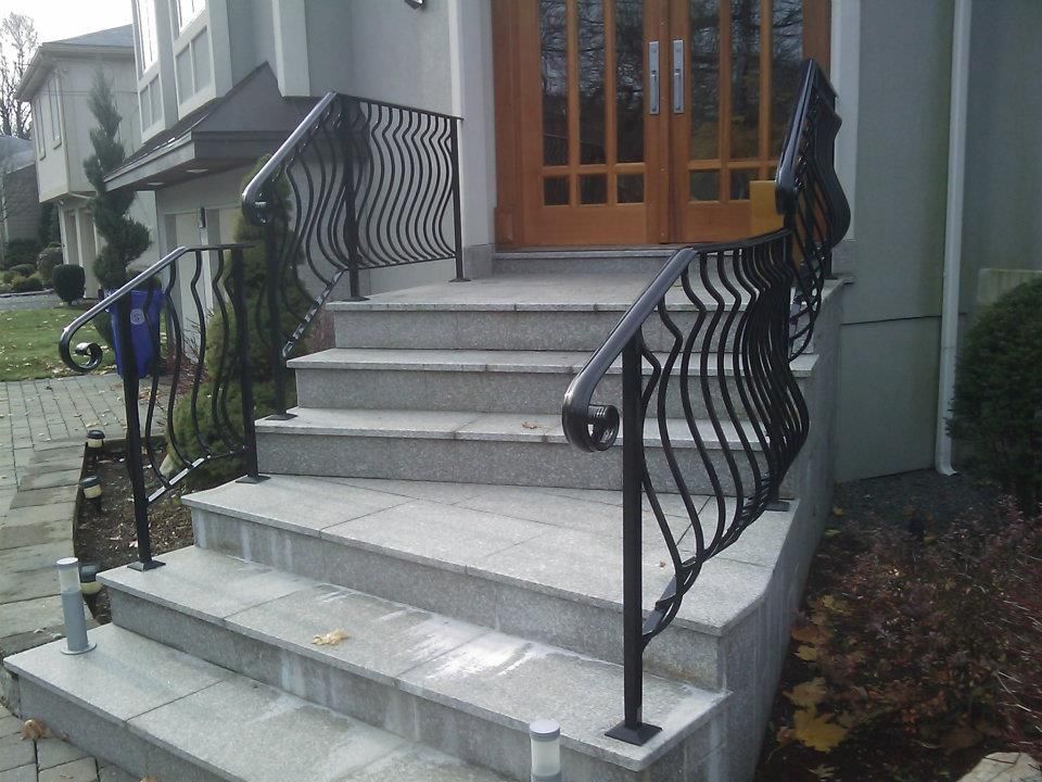Front steps with gray stone stairs and black wrought-iron railings leading to a house entrance
