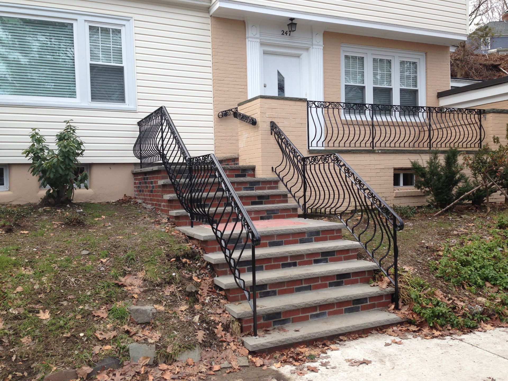 Front steps leading to a house entrance with black wrought-iron railings and brick-faced risers.
