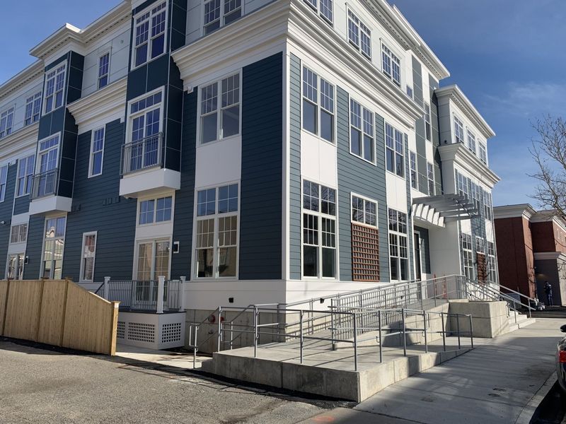 A modern blue and white multi-story building featuring an accessible metal ramp leading to the main entrance.
