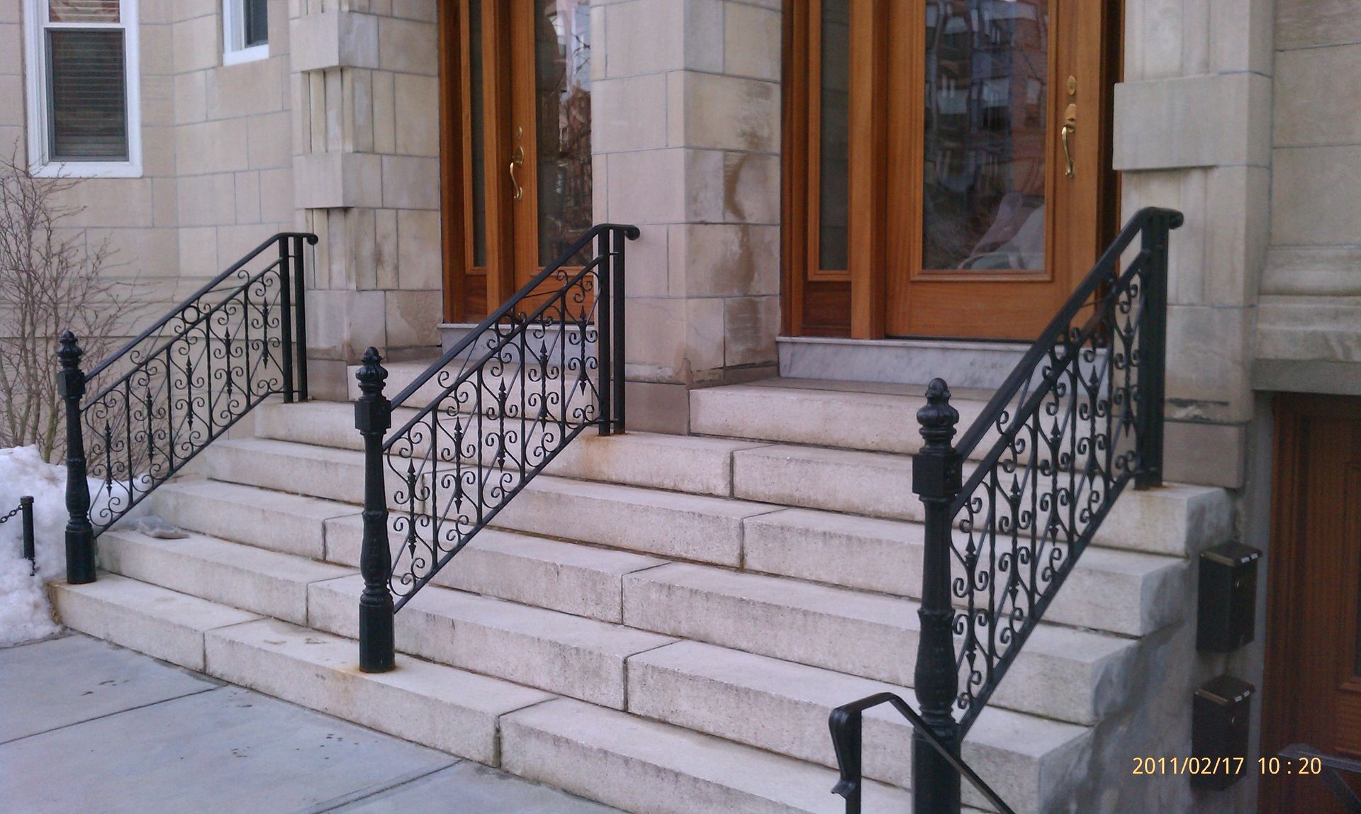 Stone staircase with black wrought-iron railings leading to a wooden front door