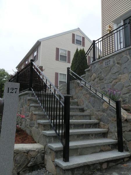 A stone staircase with black metal railings leading up to a beige house with the address 127 clearly visible.
