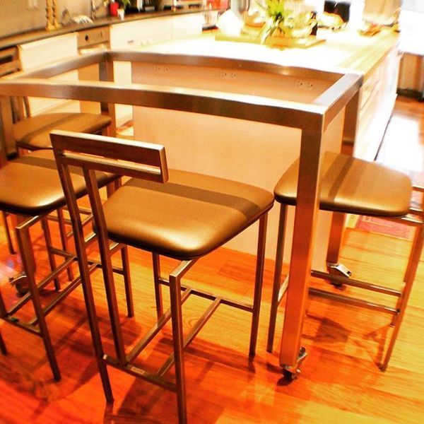 A metal-framed table with four matching stools on wooden floors in a kitchen setting.