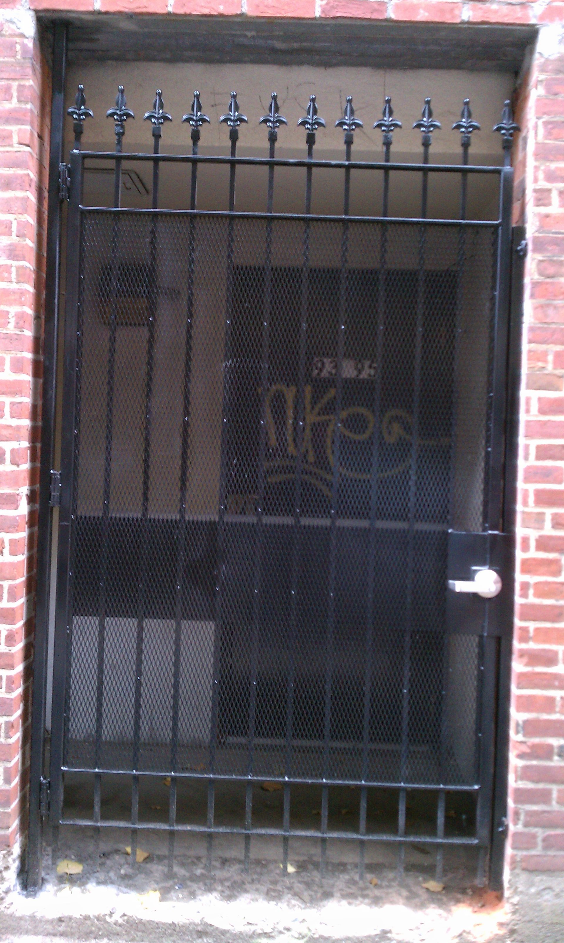 Black metal security gate on a brick doorway with a dark interior behind it