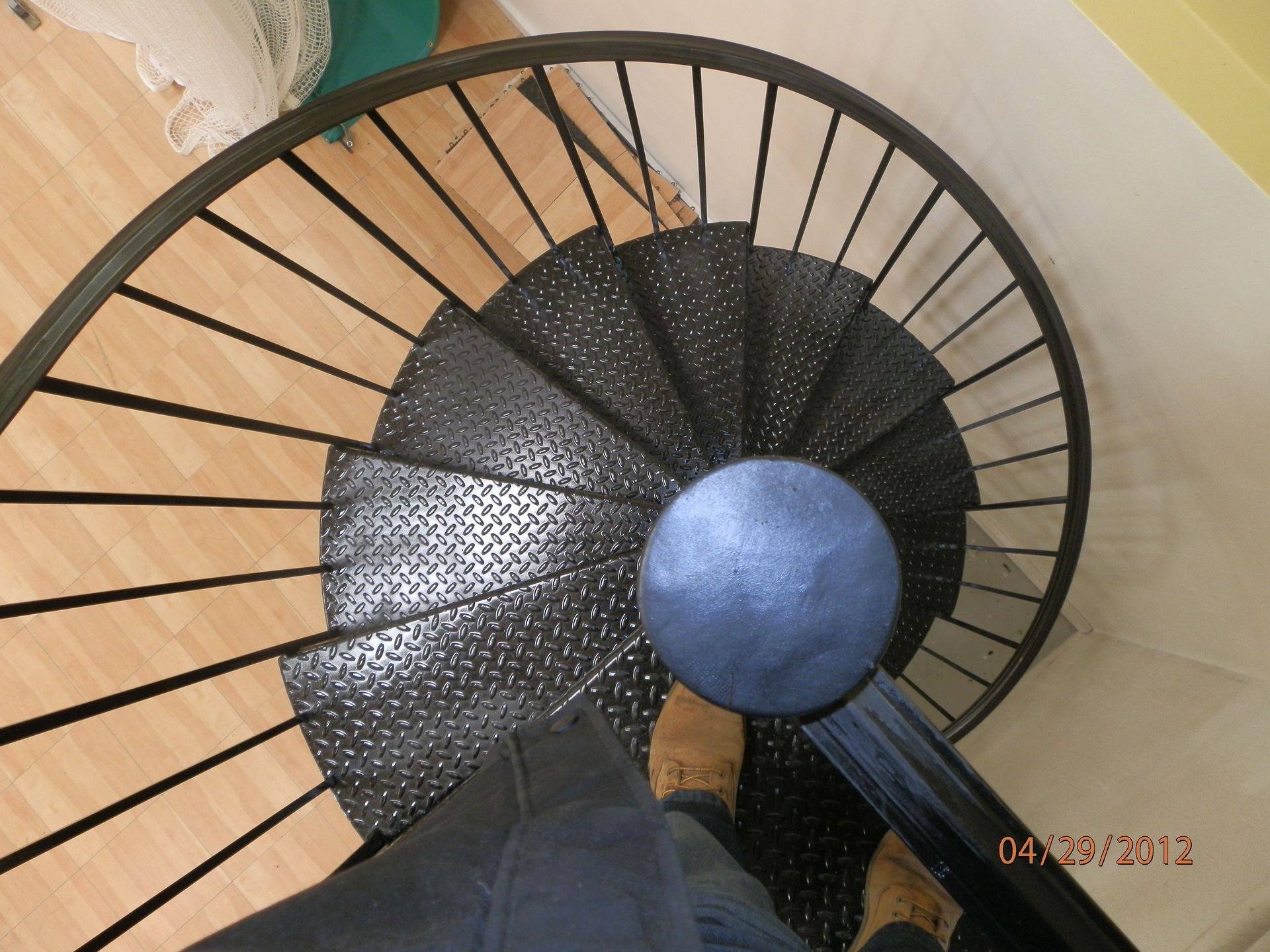 Top-down view of a black spiral staircase with a blue center in a tan-walled interior