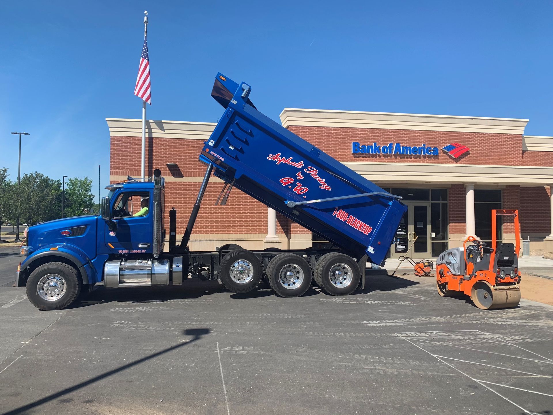 A dump truck is parked in front of a bank of America