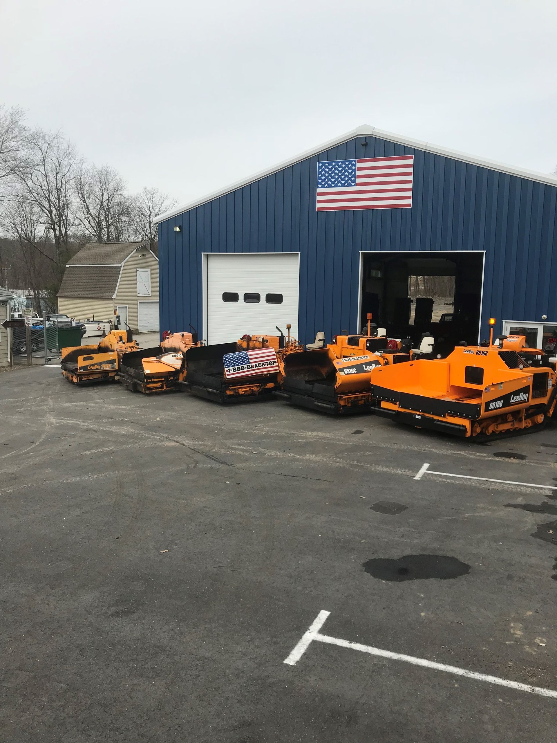 A row of tracA row of tractors parked in front of a building with an American flag on ittors parked in front of a building with an American flag on it