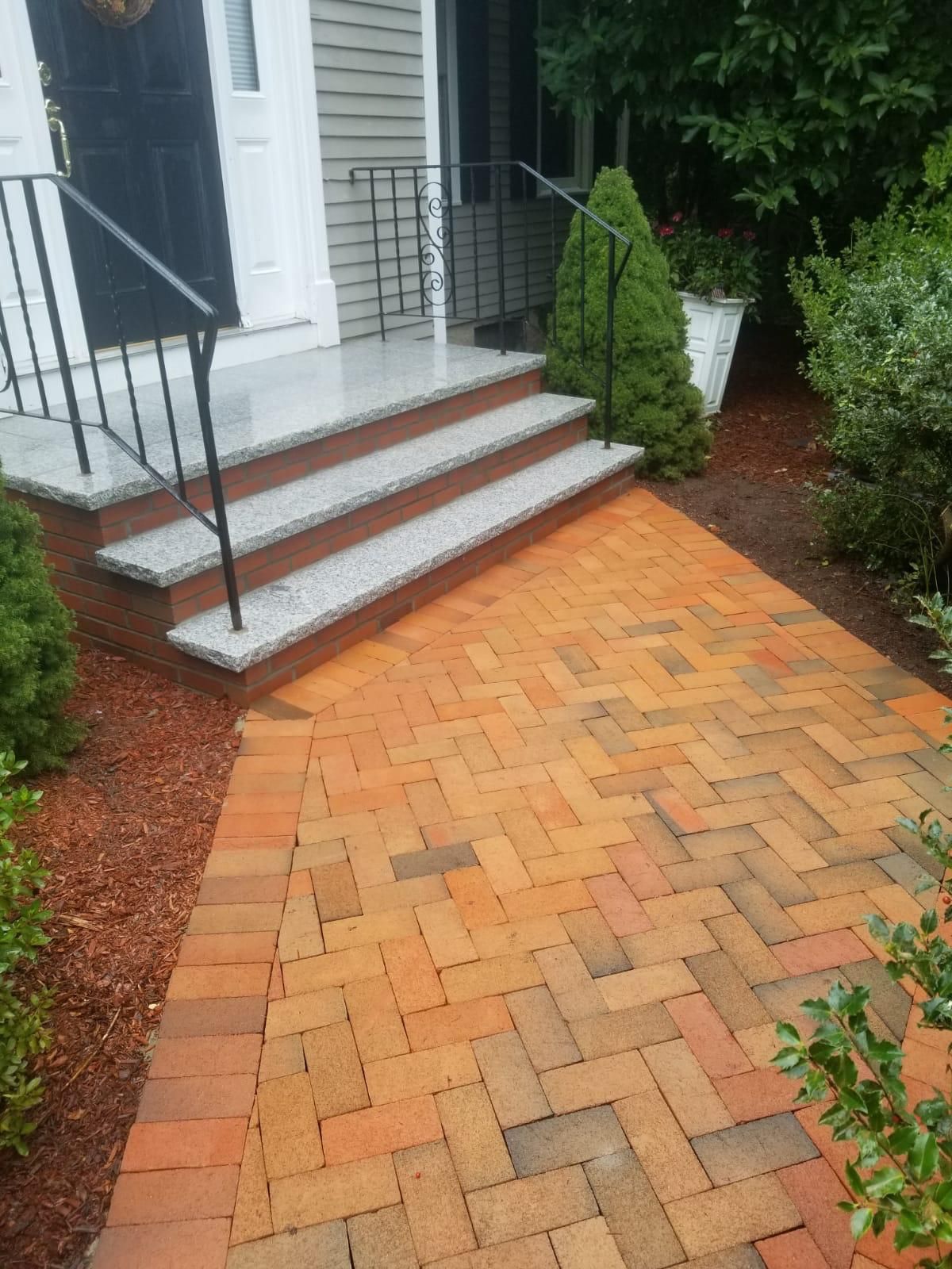 Brick pathway leading to steps and a front door.
