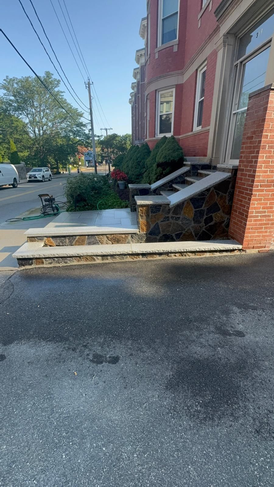 Exterior view of a building with stone steps leading to an entrance and a parking space in the foreground.