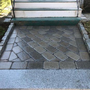 Stone walkway leading to steps of a house. Diagonal pattern of gray pavers with granite trim.