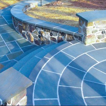 Blue stone patio with curved steps and stone wall.