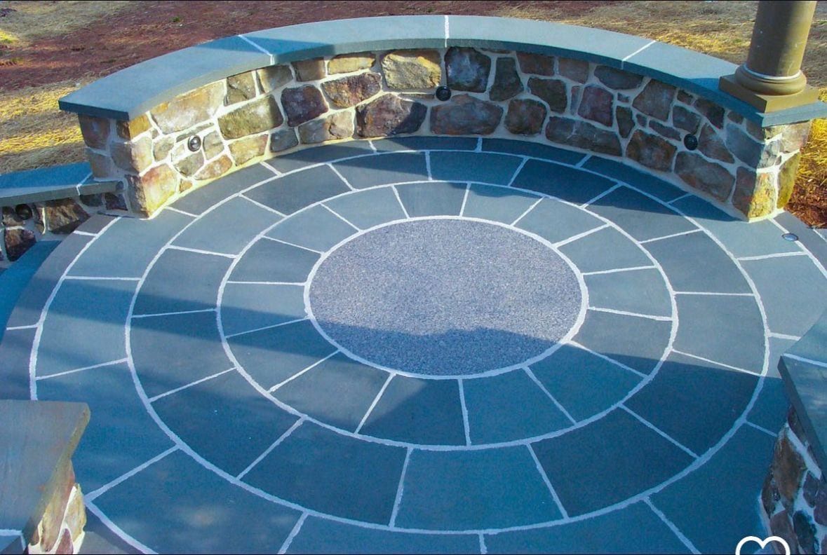 Circular stone patio with stone wall and walkway.