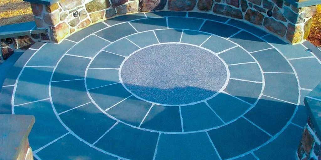 Circular stone patio with dark blue tiles and a stone wall backdrop.