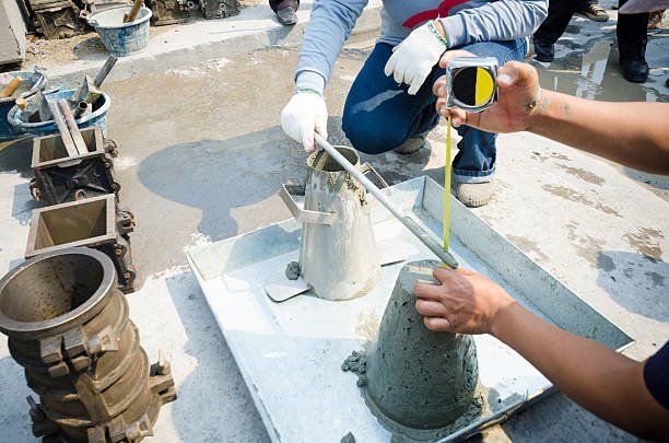 A man is measuring a concrete cone with a tape measure.
