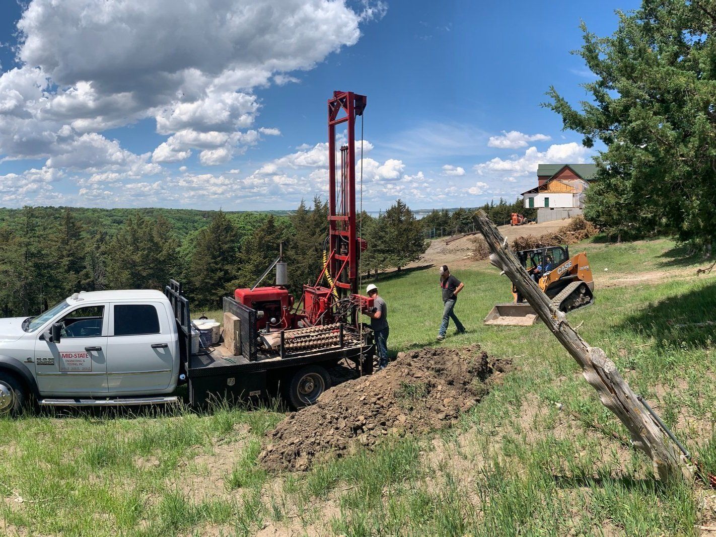A truck is parked in a grassy field next to a drilling rig.