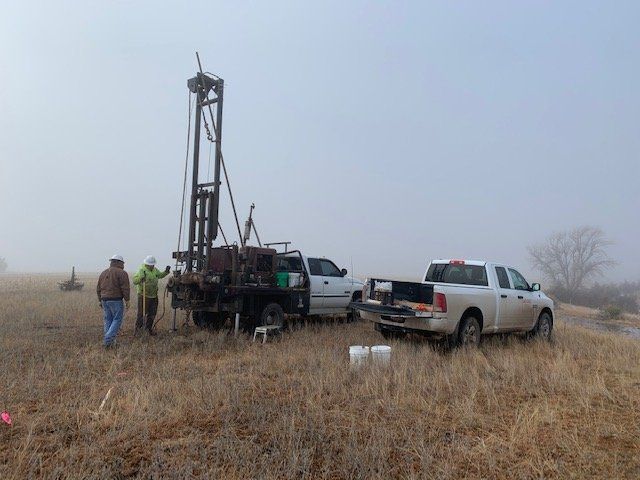 A group of people are working on a drilling rig in a field.