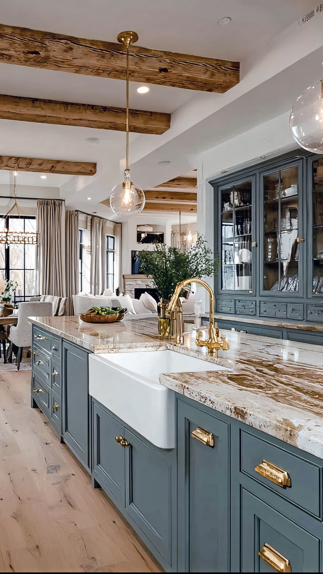 Kitchen with blue cabinetry, white farmhouse sink, and gold fixtures. Wooden beams on the ceiling.